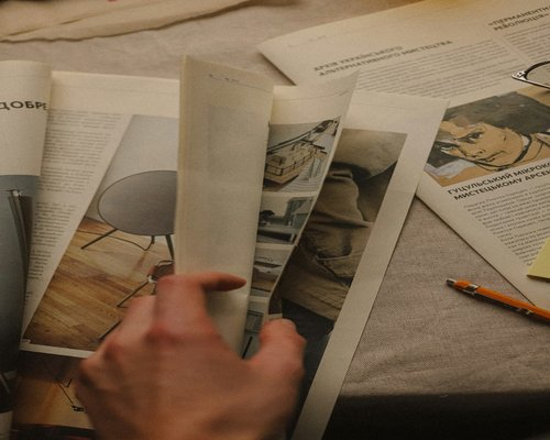 Person browsing through old newspaper archives and cultural magazines