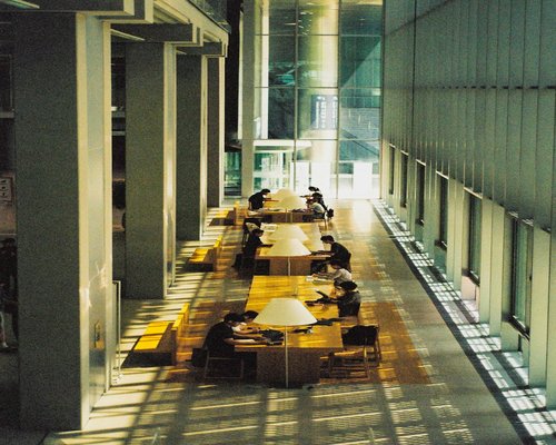 Students quietly reading books and taking notes at a long library table